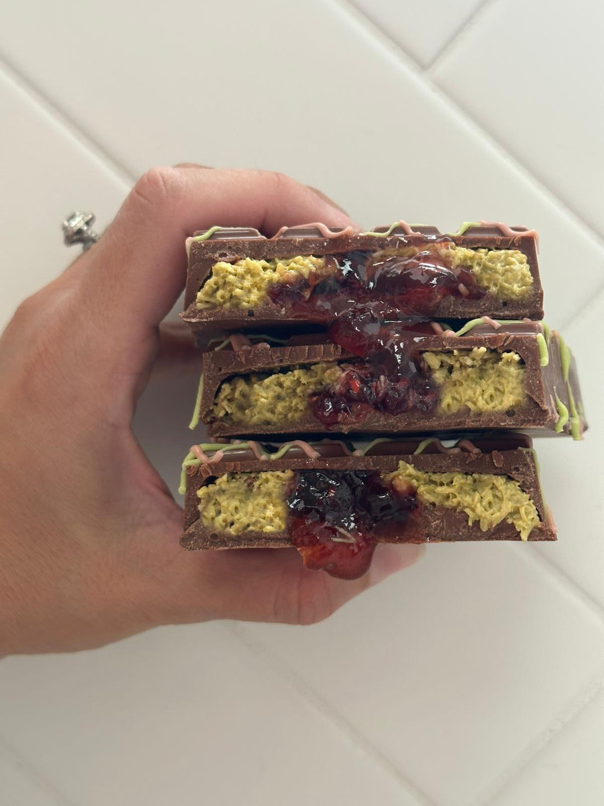 Hand Holding Opened Pistachio Raspberry Dubai Chocolate Bar